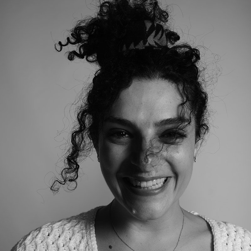 A black and white image of a Lebanese woman with dark curly hair wearing a white embroidered top.