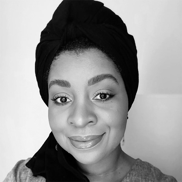 Layla Saad, a Black woman with black hair wrap smiling